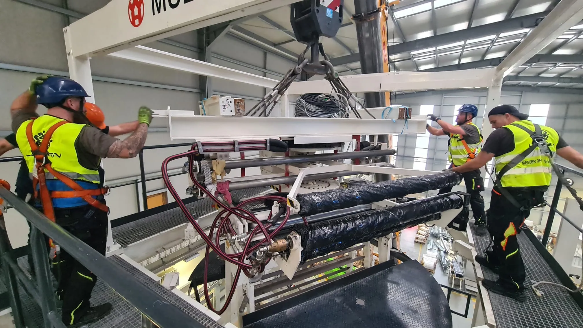 Crew guiding a suspended machine unit during unmounting
